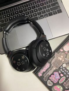 headphones sitting on top of a laptop computer next to a sticker and notebook