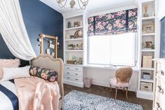 a bedroom decorated in blue and pink with flowers on the window sill, bedding, rug, dressers, and chair