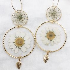 24k gold plated round dangle statement earrings made with real pressed flowers set in crystal clear resin. The small circle contains queen anne's lace, and the large circle contains a daisy. Perfect for nature lovers! These preserved botanical earrings are super lightweight and will make a statement! Pendants/charms: 24k gold plated brass Earring hoops: gold plated brass Follow us on Instagram at instagram.com/grabbagbotany to see our latest collection drops on our website, grabbagbotany.com. Th Gold Plated Flower Earrings For Weddings, Gold Plated Round Flower Earrings For Wedding, Gold Nickel-free Flower Earrings As Gift For Her, Delicate Pressed Flower Jewelry, Botanical Jewelry With Pressed Flowers, Gold Earrings With Flower Charm As Gift For Her, Gold Earrings With Flower Charm For Her, Botanical Drop Earrings With Birth Flower, Botanical Birth Flower Drop Earrings