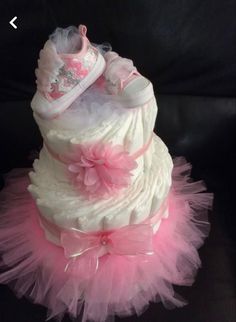 a pink and white diaper cake with baby shoes on it's bottom tier