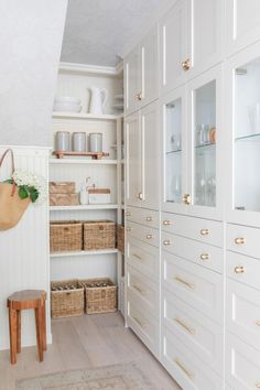 an open closet with white cabinets and wicker baskets on the bottom shelf is shown