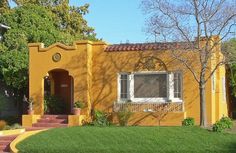 a yellow house with steps leading up to the front door and windows on each side