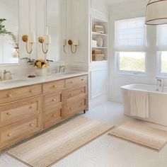 a bathroom with two sinks, a bathtub and a rug on the floor in front of it