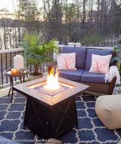 a fire pit sitting on top of a patio next to a couch and table with pillows