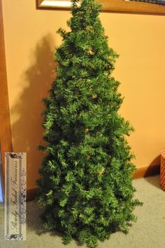 a small green christmas tree sitting next to a wall