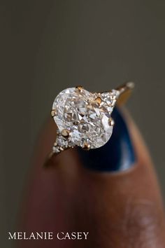 a close up of a person's hand holding a ring with a diamond in it