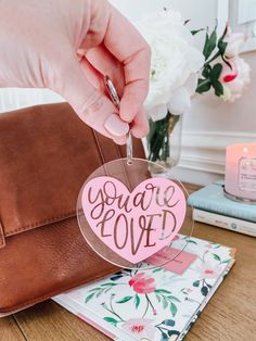 a person holding a heart shaped card with the words you're loved on it