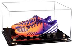 an orange and purple soccer shoe in a clear display case on top of a black base