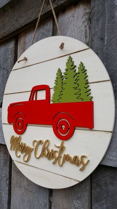 a christmas sign hanging from the side of a wooden door with a red truck and pine tree on it