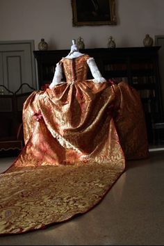 Luxurious, opulent, the pinnacle of 18th century dress, the court dress dedicated to queens and princesses of "blood". Made of red and gold brocade fabric, it has a 4-meter train and lace inserts and antique braids. It is a faithful reproduction made with high quality materials and criteria. Italian size 42/44 Victorian Brocade Dress With Historical Design, Baroque Gown With Historical Design For Costume, Historical Baroque Gown For Costume Use, Regency Style Gold Dress With Historical Design, Gold Brocade Fabric, 18th Century Dress, Century Dress, Court Dresses, Gold Brocade