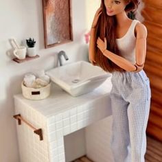 a barbie doll standing in front of a bathroom sink