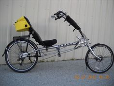 a bicycle parked next to a building with a yellow box on the back tire and seat