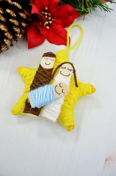 a christmas ornament with two people hanging from it's side next to a pine cone