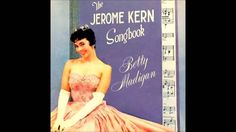 a woman in a pink dress sitting on top of a purple sheet music album cover