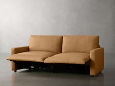 a couch with two reclinings on it in front of a gray wall and floor