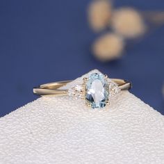 a ring with an oval cut aquamarinee stone and two diamonds on the side