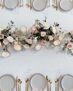 the table is set with white plates and silverware, gold place settings and flowers