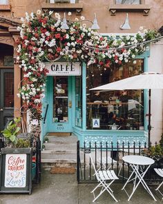 an outdoor cafe with flowers growing over the front door and tables in front of it