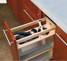 an open drawer in a kitchen with utensils and pans on the bottom shelf