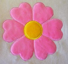 a pink flower with yellow center sitting on top of a white sheet