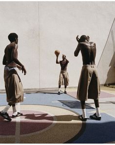 two men in brown outfits playing basketball on a court with another man standing behind them