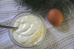 a glass bowl filled with cream next to an egg on top of a white cloth