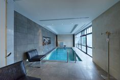 an indoor swimming pool in the middle of a large room with chairs and a bench