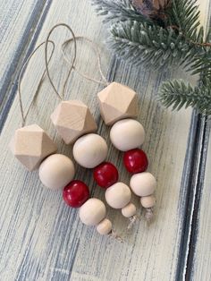 small wooden ornaments on a table next to a pine tree and fir branch with red berries