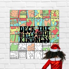 a woman wearing a santa hat standing in front of a brick wall with the words deck the table with kindness on it