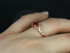 a woman's hand with a ring on it and a red stone in the middle