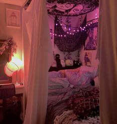 a bed with purple lights hanging from it's ceiling and pillows on the floor