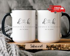 two personalized coffee mugs sitting on top of a wooden table next to a blanket