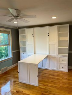 an empty room with white cabinets and wood floors