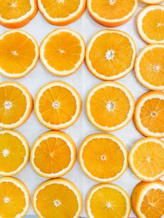 many oranges are arranged in rows on a sheet of white paper with the top half cut open