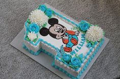 a mickey mouse birthday cake with blue flowers on the bottom and white frosting around it