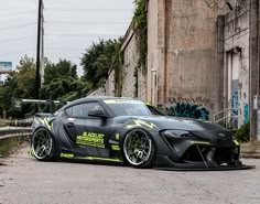 a black sports car parked in front of an old building with graffiti on the walls