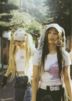 two young women walking down the street with skateboards on their heads and long hair