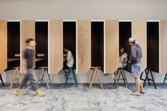 people are sitting at tables and standing in front of wooden partitions on the wall