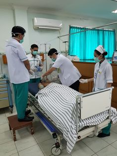 medical personnel performing surgery in an operating room with patient on the bed and another person standing next to him