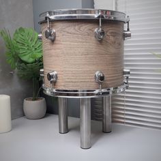 a wooden drum sitting on top of a table next to a potted plant