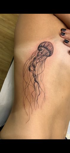 a woman's stomach with a tattoo of a jellyfish on her left side