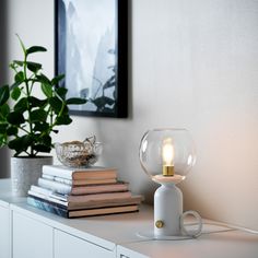 a table with some books and a lamp on it next to a potted plant