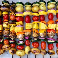 several skewers of vegetables and potatoes on a white table top, ready to be grilled