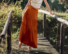 Our exquisite Pure Silk Tiered Maxi Skirt in Tuscan Orange is our newest dreamy addition to our collection and an absolute must-have. Designed by us in Europe and crafted with utmost care by our fine silk artisans, this skirt is elegant, sophisticated and on trend with the gorgeous rust colour that is THE colour of the season. Made from 16 momme silk which has the most luxurious feel, this skirt offers a floaty drape that gracefully flows with every step you take. The sandwash finish adds a subt Orange Maxi Skirt, Rust Colour, Skirt Flowy, Evening Cocktail Party, Long Flowy Skirt, Skirts Flowy, Long Skirt Summer, Silk Maxi Skirt, Party Rock