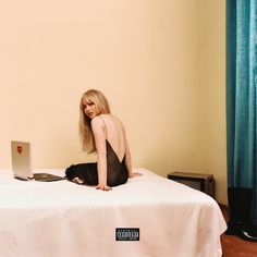 a woman sitting on top of a bed with a laptop computer in front of her