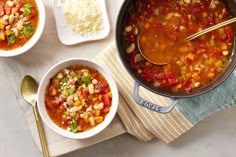 two bowls of soup with spoons next to each other on a wooden board and towel