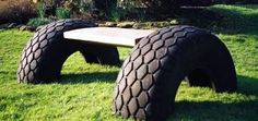 two large tires sitting on top of green grass next to a wooden bench in the middle of a field