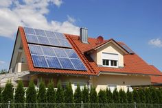 a house with solar panels on the roof and red tiles on the shingled roof