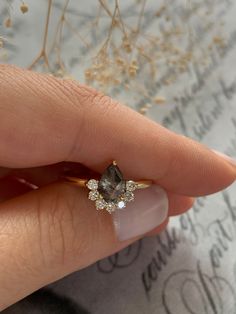 a woman's hand holding an engagement ring with a brown diamond on the side