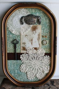 an old fashioned frame with lace doily and pictures on the front, hanging on a wall